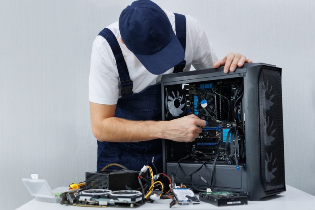 A computer engineer in uniform repairs a personal computer.